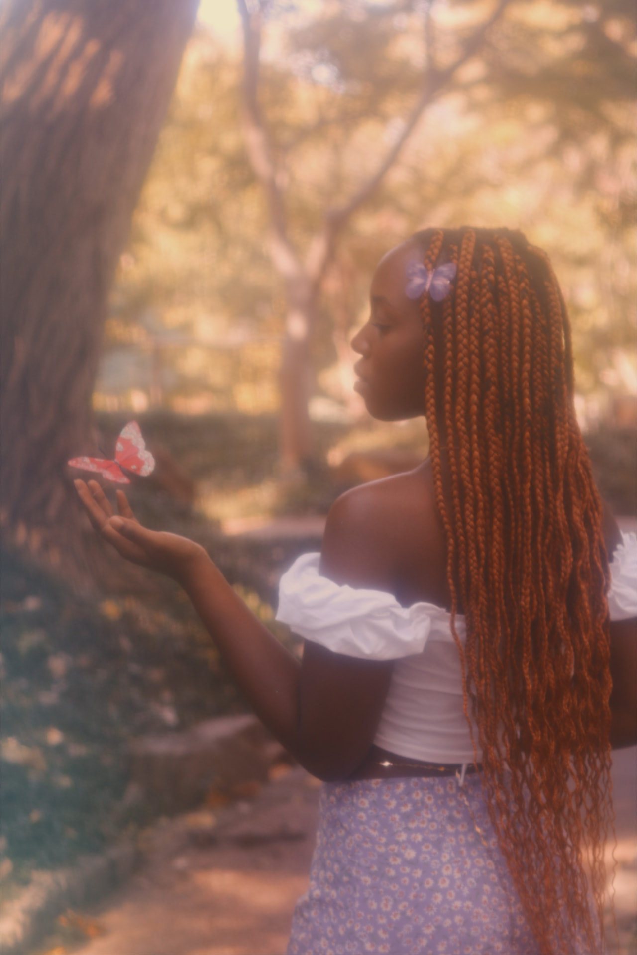 Profile of a woman with copper braids holding a paper butterfly