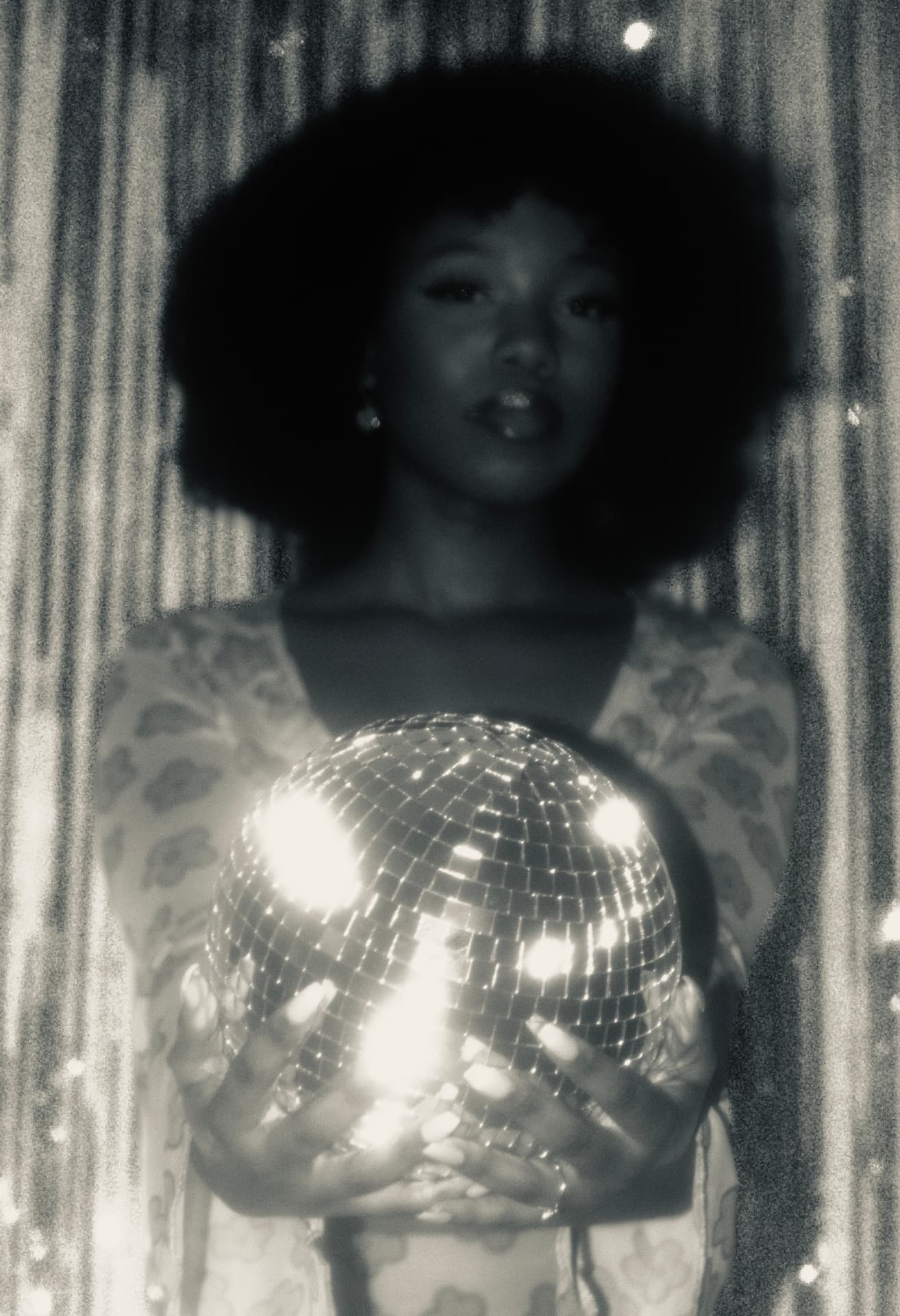 Woman cradling a glittering mirrorball in black and white