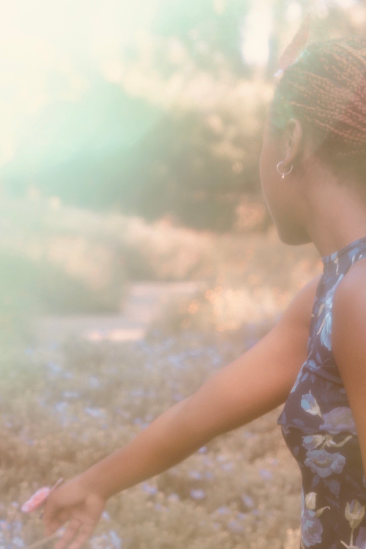 Woman reaching toward wildflowers in soft green sunflare